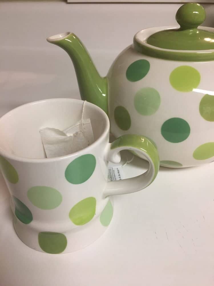 Green and white polka dot teapot and teacup - tea is great if you're wondering how to cure a cold.