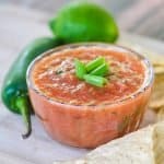 Best homemade salsa topped with green onions in a small clear bowl.