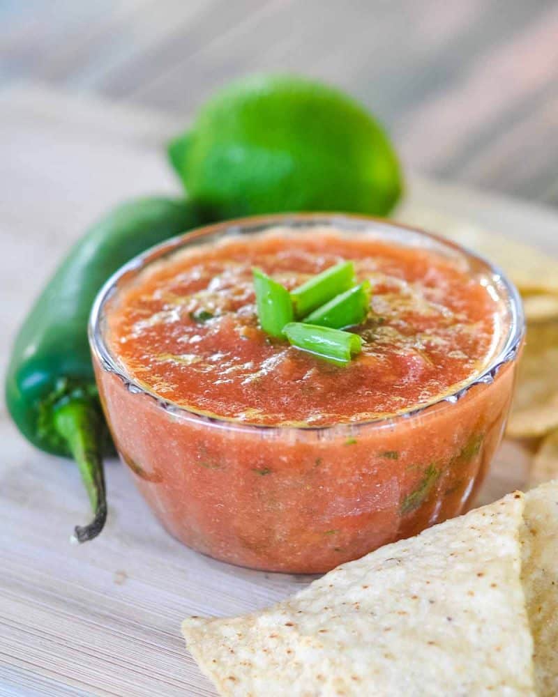 Best homemade salsa topped with green onions in a small clear bowl.