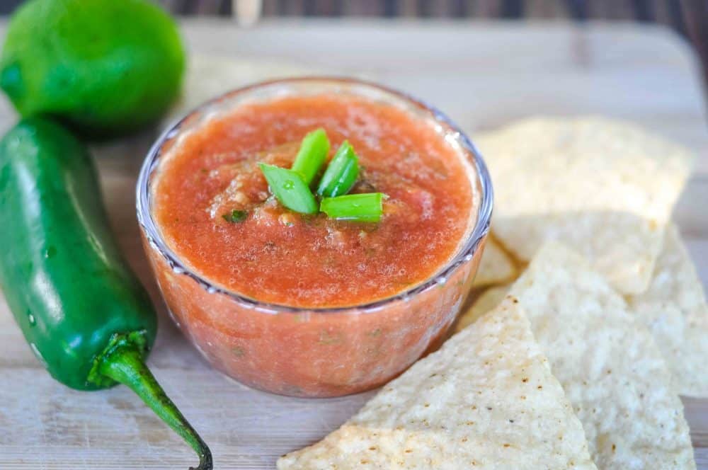 Easy homemade salsa in a ramekin next to jalapeno pepper.