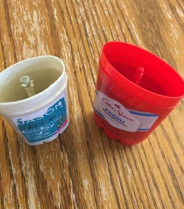 Two empty homemade deodorant stick canisters on a wood surface.