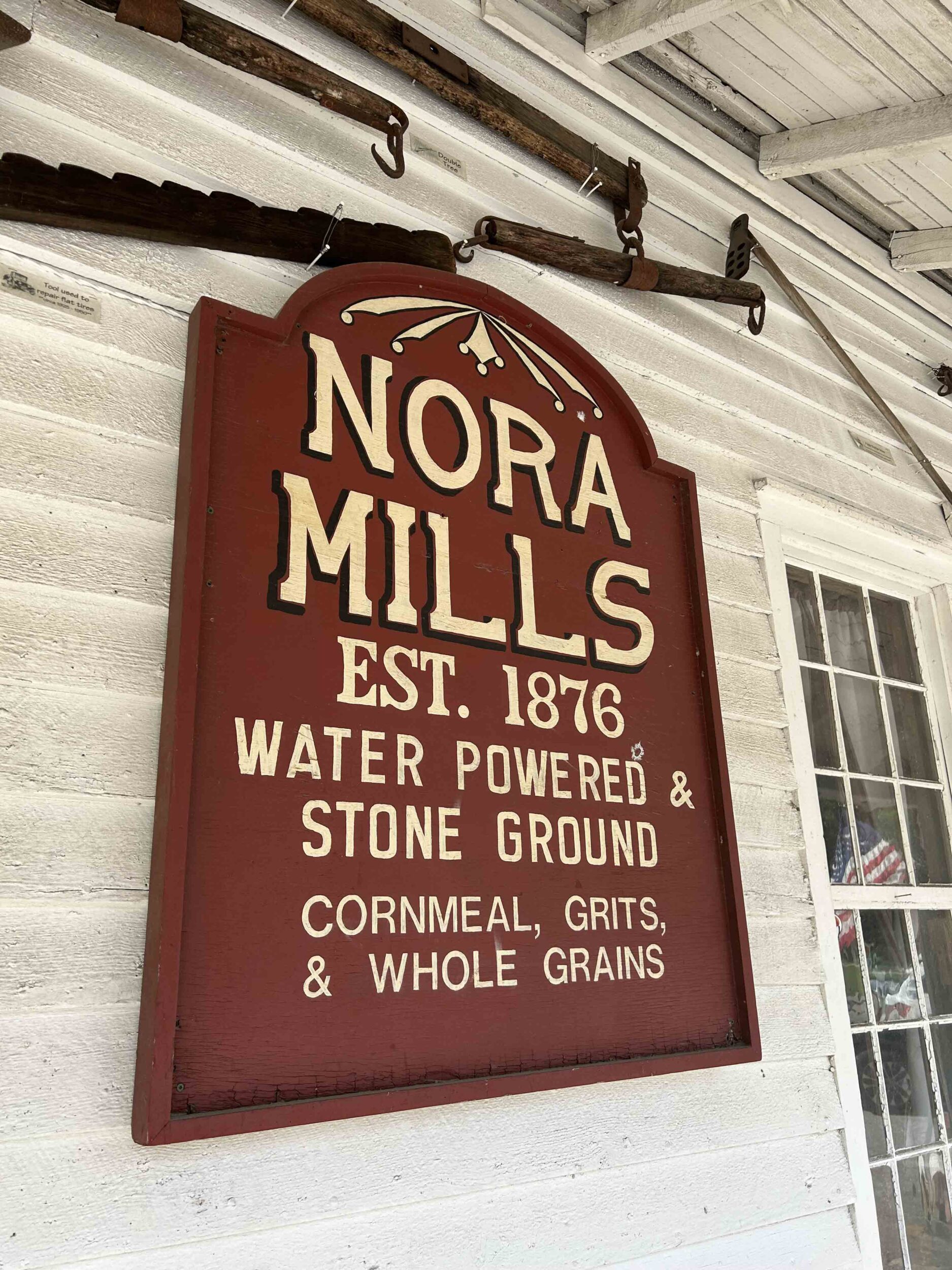 Wooden sign at a grist mill that says Nora Mill Granary, Stone Ground Cornmeal.