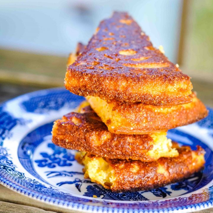 best cornbread recipe slices stacked on a blue willow plate.