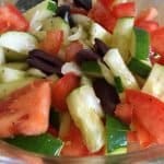 Tomato cucumber onion salad in a large glass bowl.
