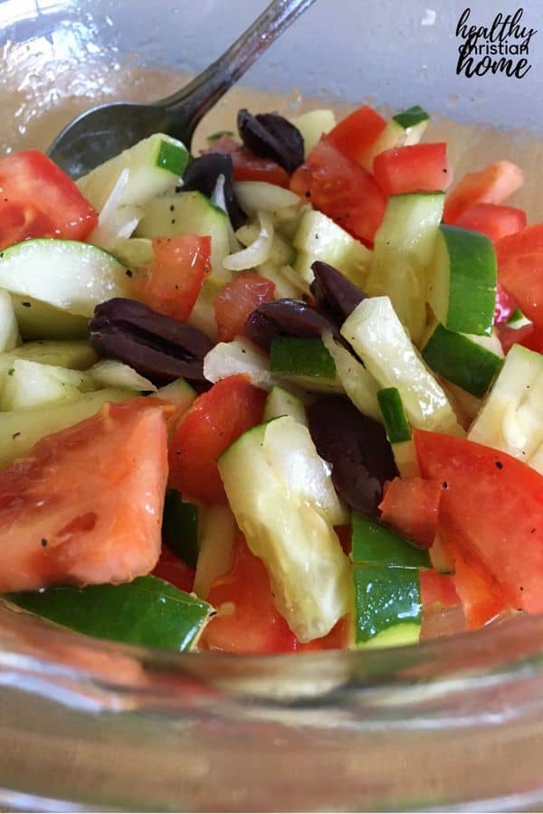 Tomato cucumber onion salad in a large glass bowl.