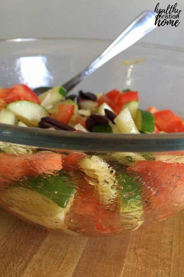 Summer vegetable salad with tomato, cucumber, onion and olives in a large bowl.