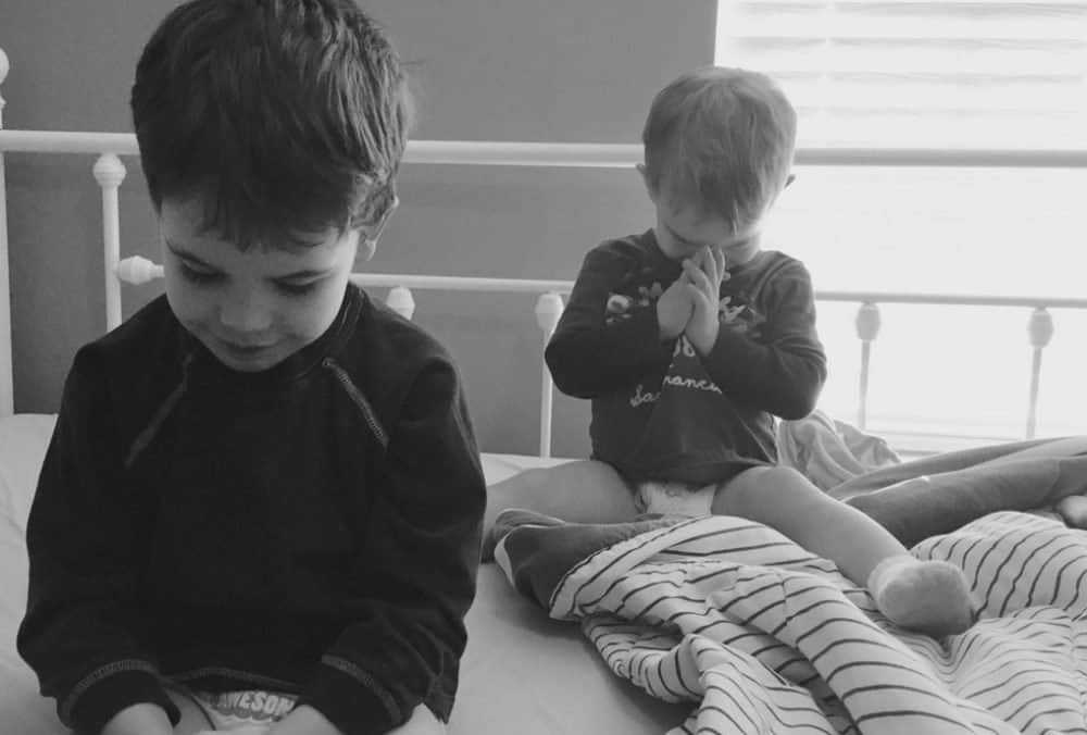 Bible study for kids during prayer time. Black and white photo of two little boys bowing their heads to pray.