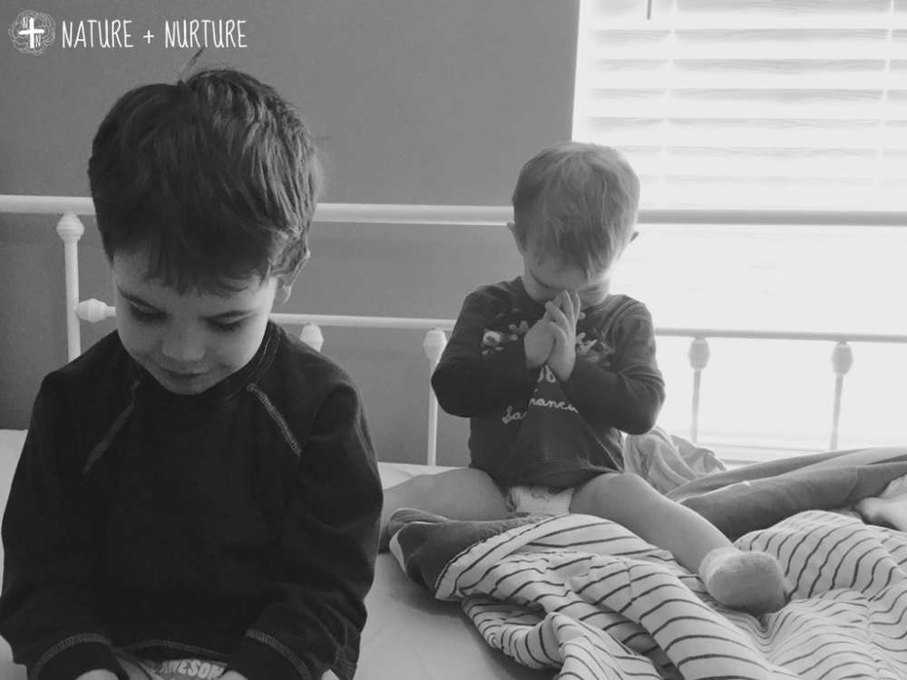 How to teach your child about God through prayer, two little boys praying on a bed.