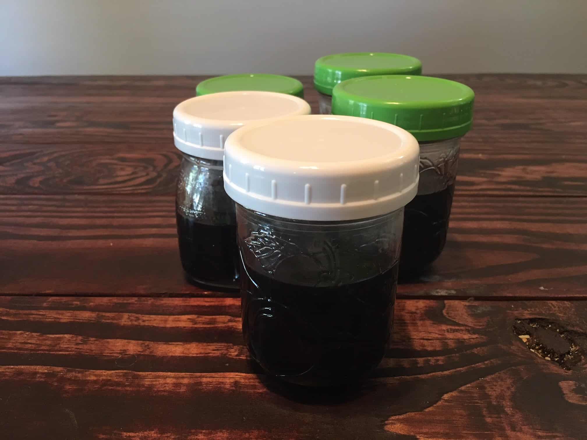 Mason jars filled with homemade elderberry syrup, a great remedy against common cold symptoms