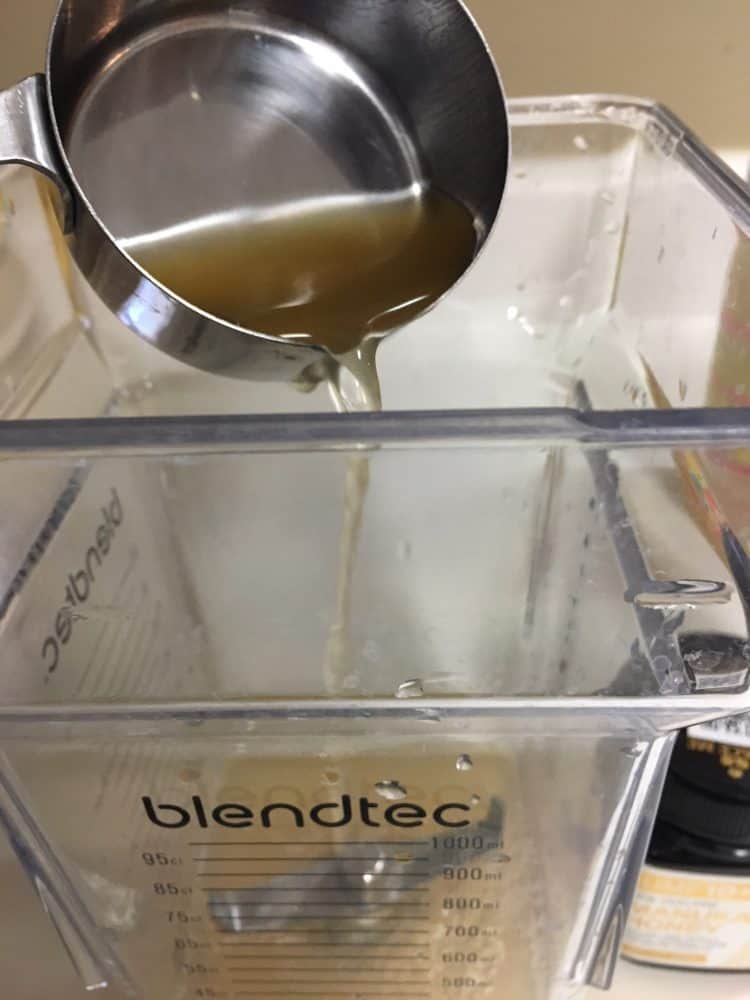 Apple cider vinegar pouring into a blender.