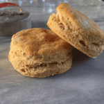 Two golden homemade biscuits on a marble platter - mastering baking is great for learning how to save money.