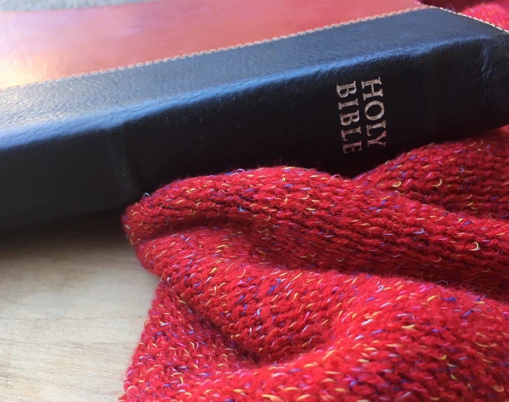 Red and black leather bible next to a red blanket