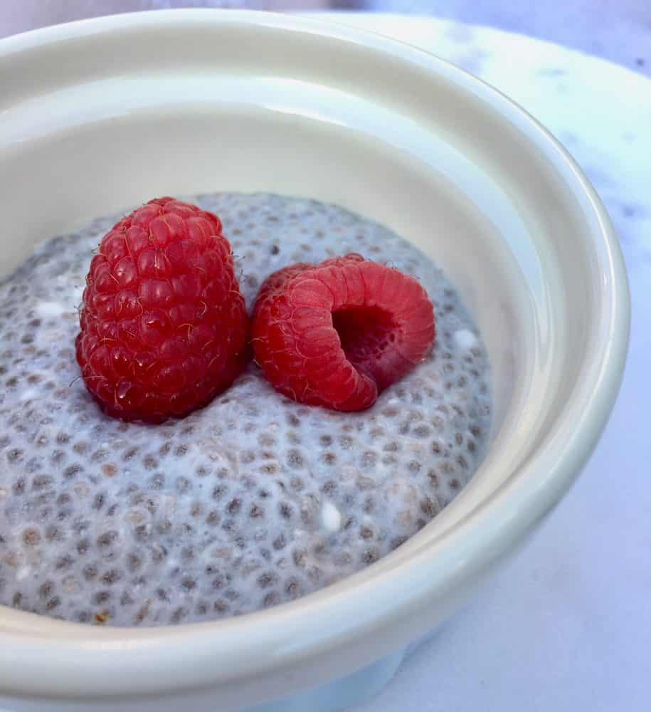 One of the easiest chia recipes - coconut milk and chia pudding in a small bowl topped with raspberries.