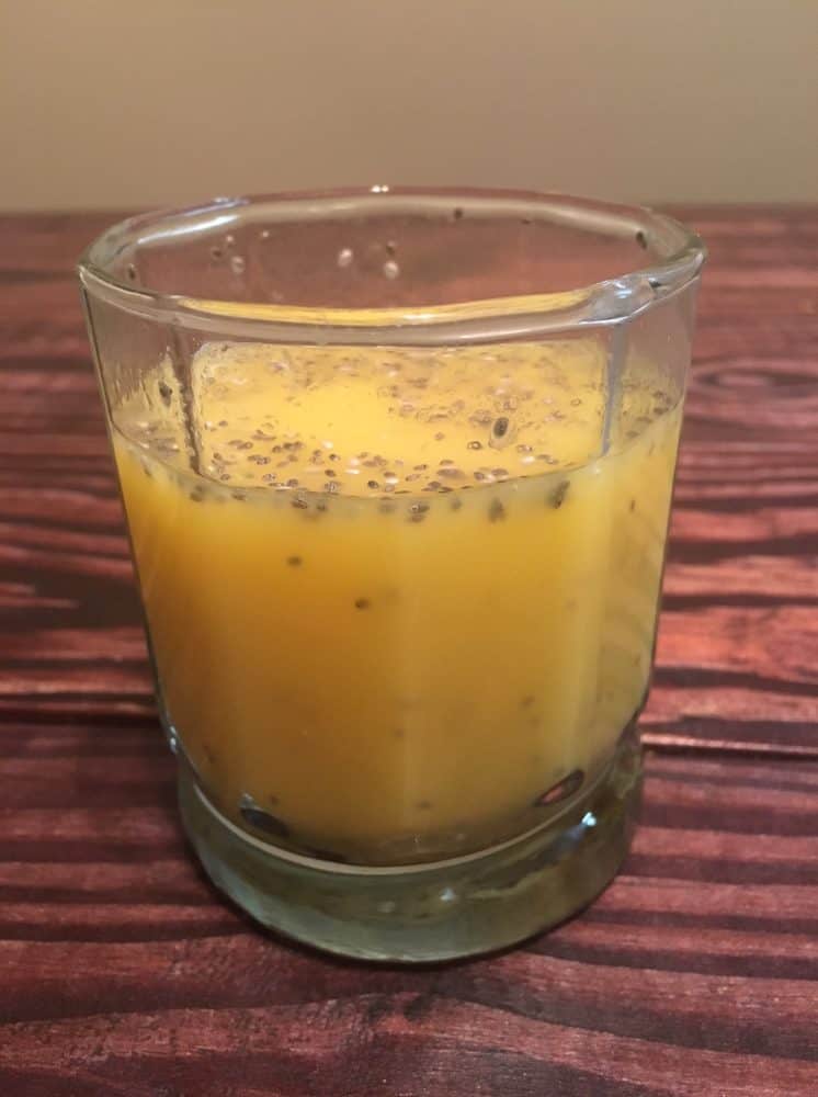 Small glass on a wooden table filled with orange juice and chia seeds - one of the simplest chia recipes.