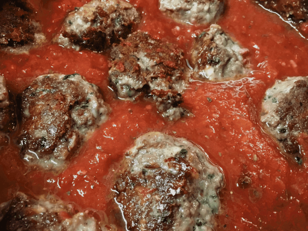 Homemade meatballs in marinara sauce, bubbling in a slow cooker.