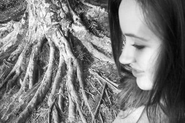 Black and white photo of a Christian wife in profile, next to a large tree root system. 