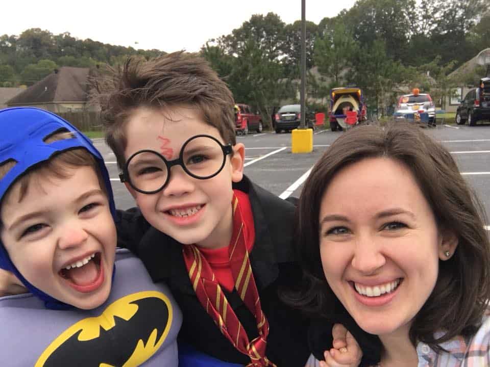 Two sons dressed up for halloween, smiling with their mother.