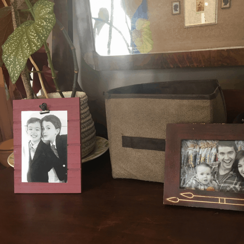 The top of a dresser with a plant, picture frames, and an organizing bin to keep things tidy.