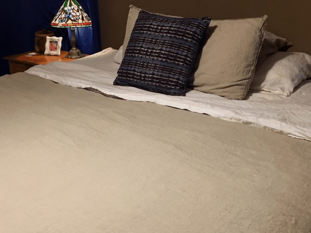 King size bed with linen bedding and a decorative bedside lamp.