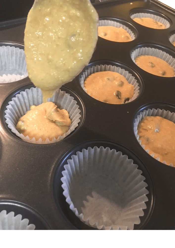 Filling a muffin tin with breakfast muffins batter. 