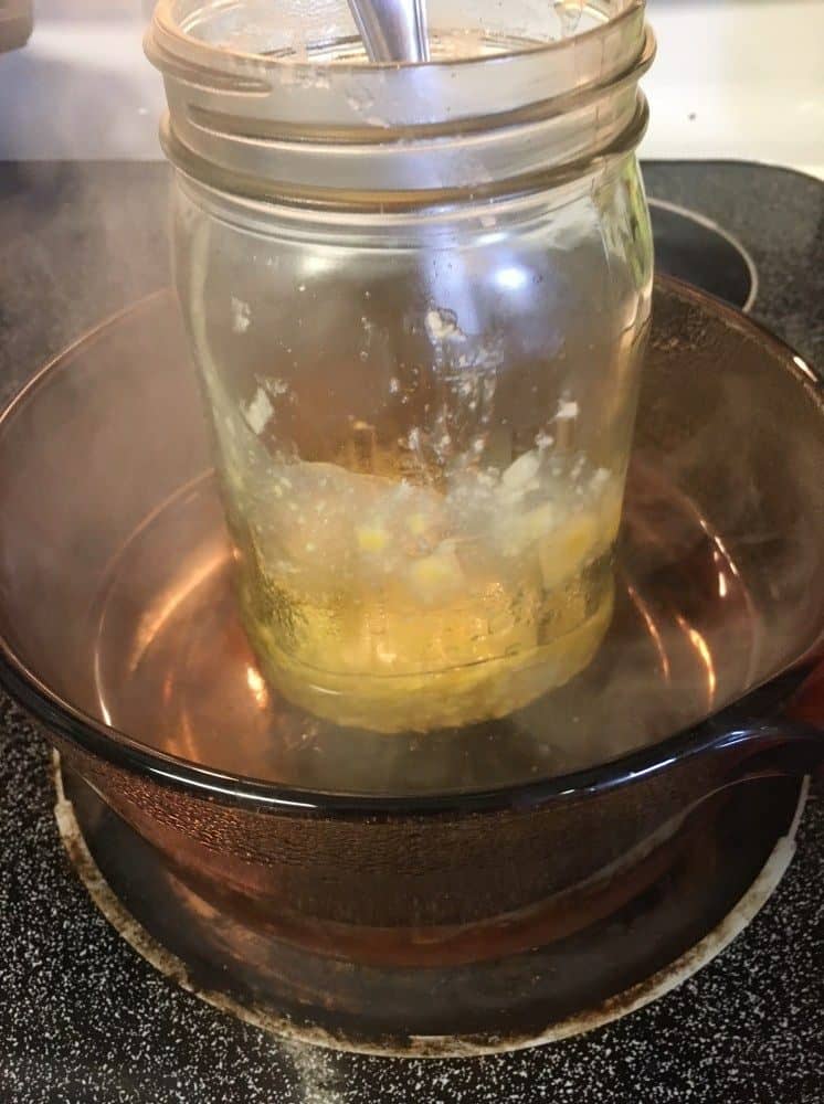 Magnesium salve melting in a large jar inside a pot of simmering water.