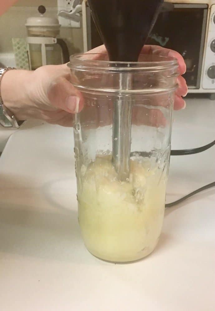 Whipped magnesium lotion in a jar, being whipped by hand wth an immersion blender.