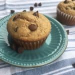 Chocolate chip peanut butter breakfast muffins on an antique blue plate with chocolate chips and another muffin in the background.