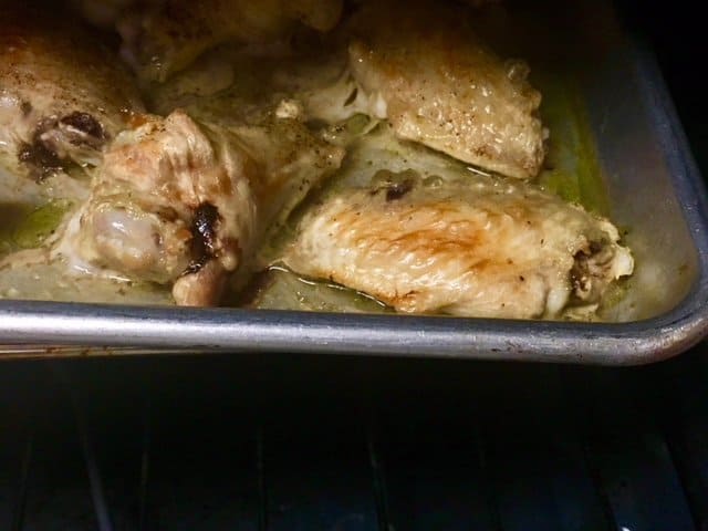 Baking frozen chicken wings in an oven. Close-up shot of a chicken wing turning golden-brown.