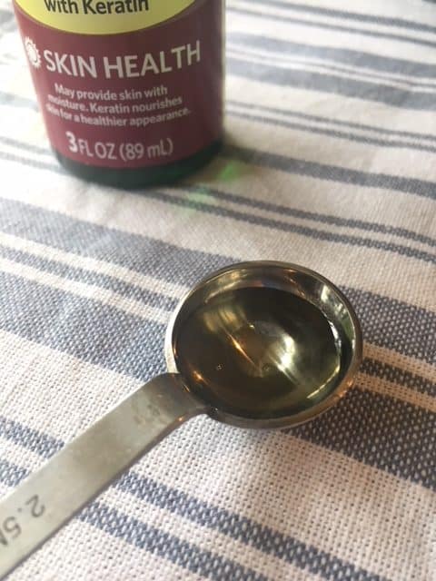 Vitamin E oil in a silver measuring spoon, ready to be used in homemade body lotion