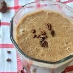 Homemade chocolate smoothie in a small glass, garnished with cacao nibs.