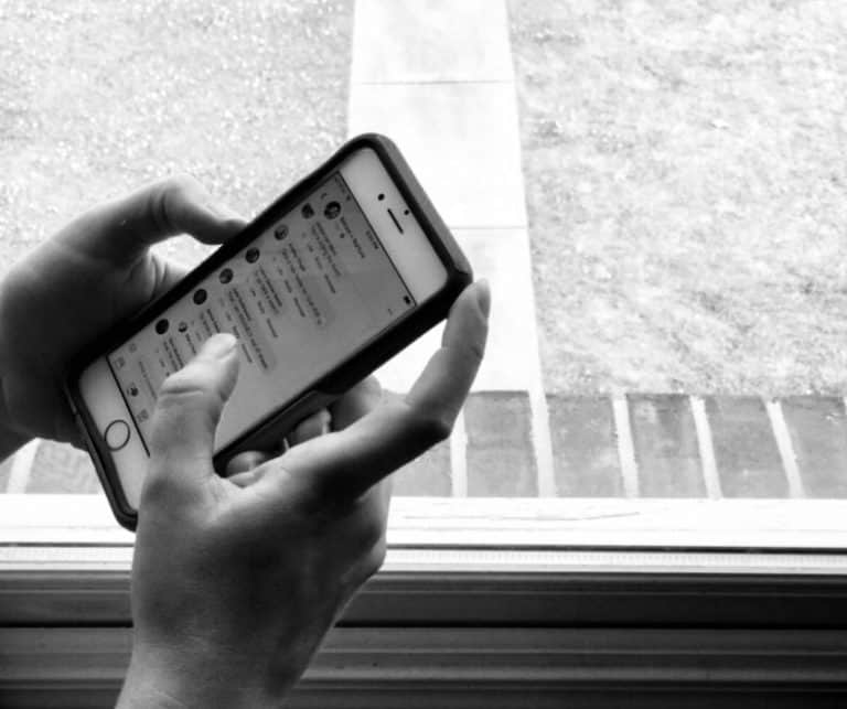 Close-up of a person's hands holding a mobile device, scrolling through social media.