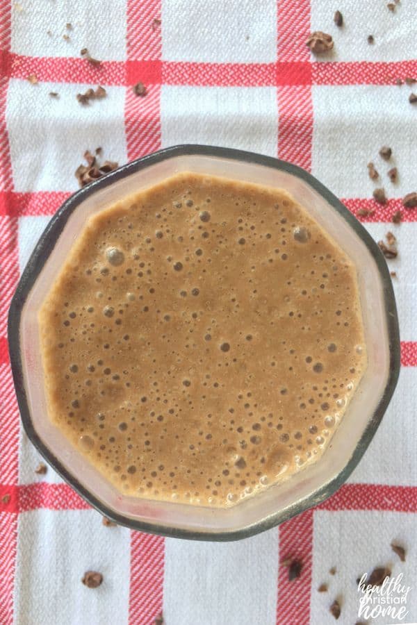 Chocolate smoothie in a small glass cup on a red checkered cloth.