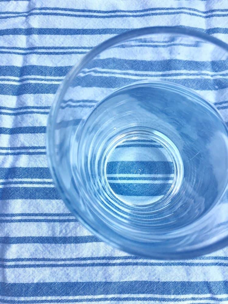 How much water should I drink? A glass of water on a striped tea towel.