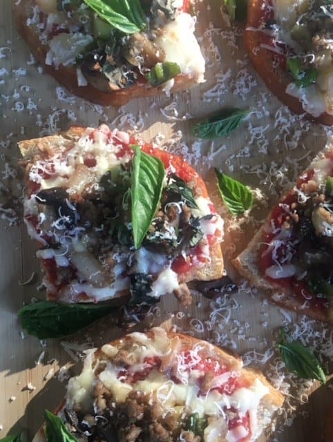 Sourdough homemade mini pizzas on a wooden board with fresh basil.