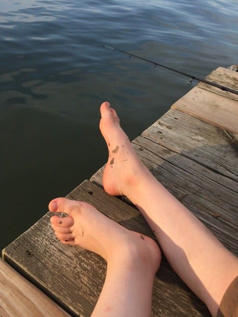 Childs feet on the edge of the dock at the lake.