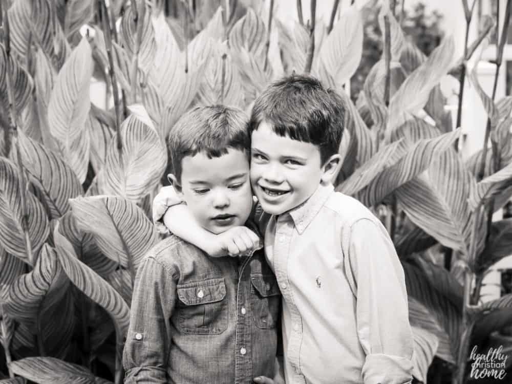 Black and white photo of an older brother hugging his younger brother.