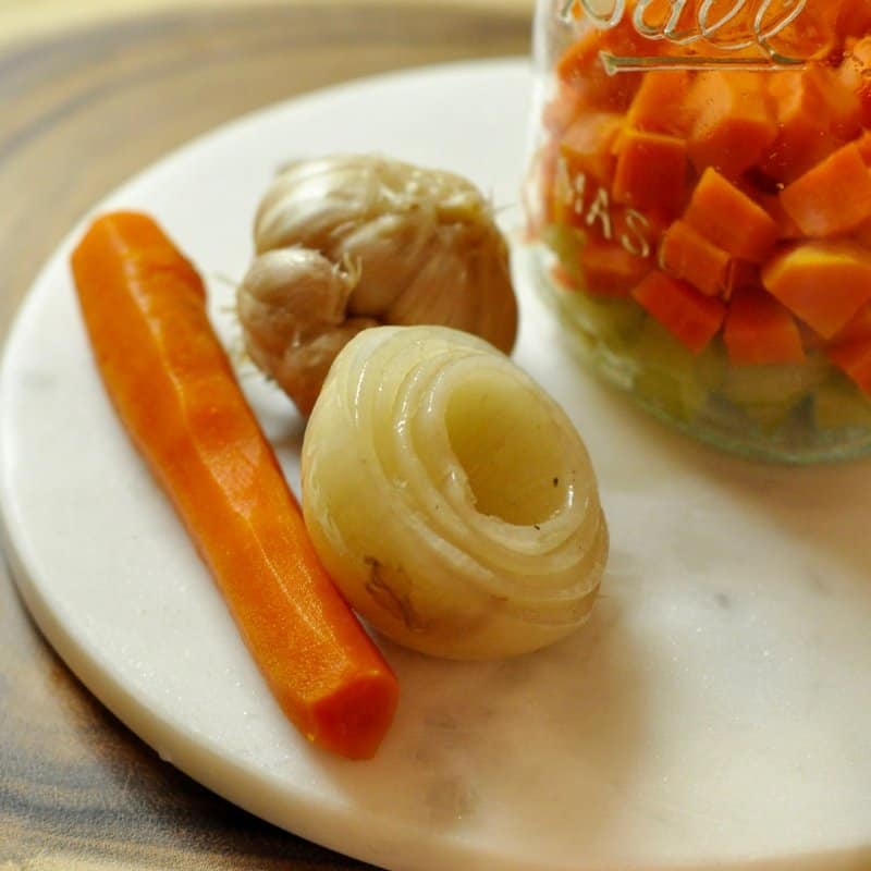 Weich gekochtes Gemüse auf einer Platte: Karotten, Zwiebeln und Knoblauch.