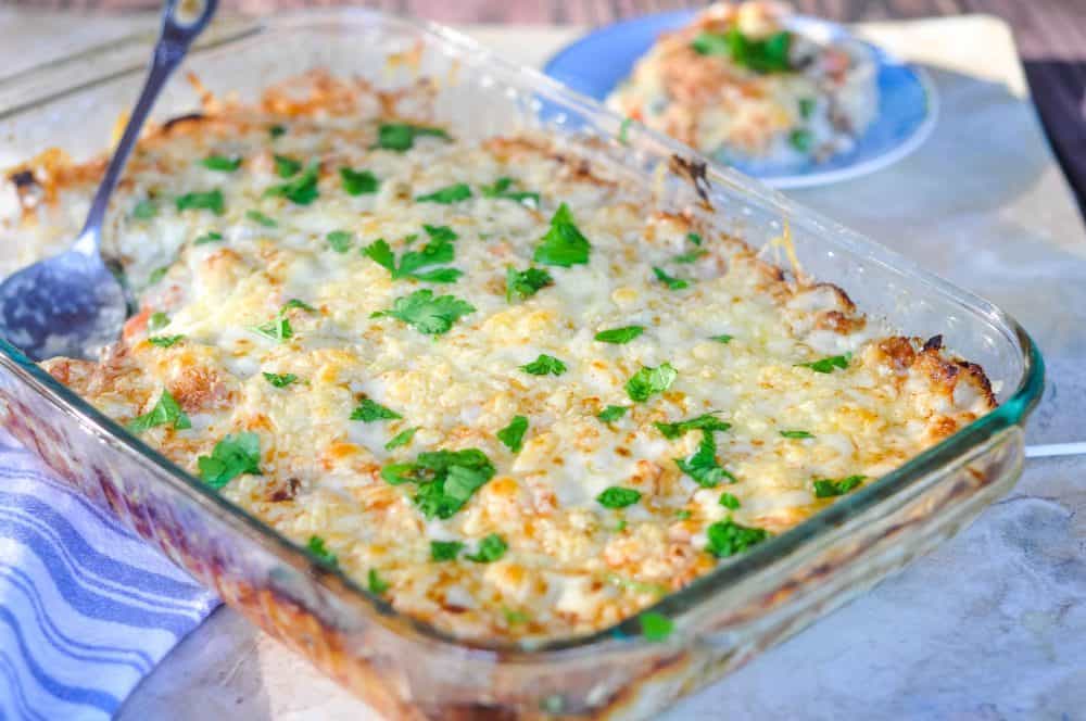 Chicken pot pie casserole in a glass dish covered with cheese.