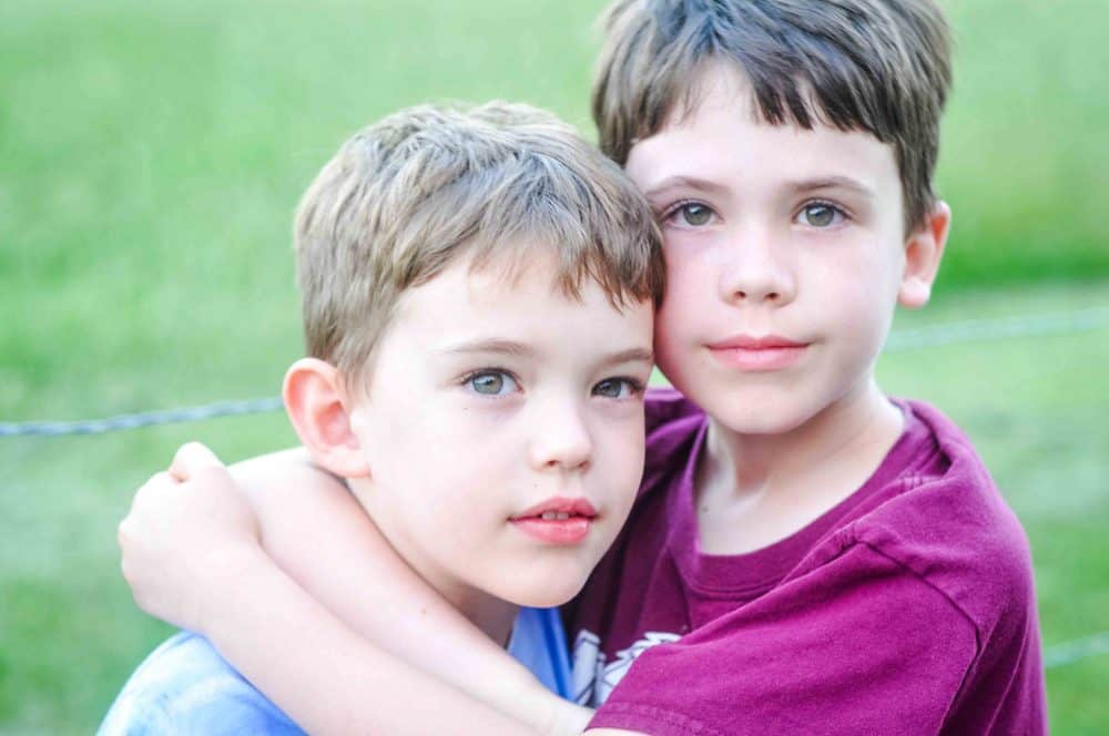 Two brothers side by side in nature.