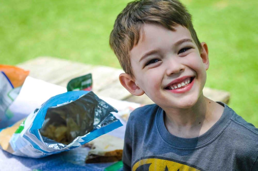 Child eating a picnic lunch, the perfect way to experience nature for kids.