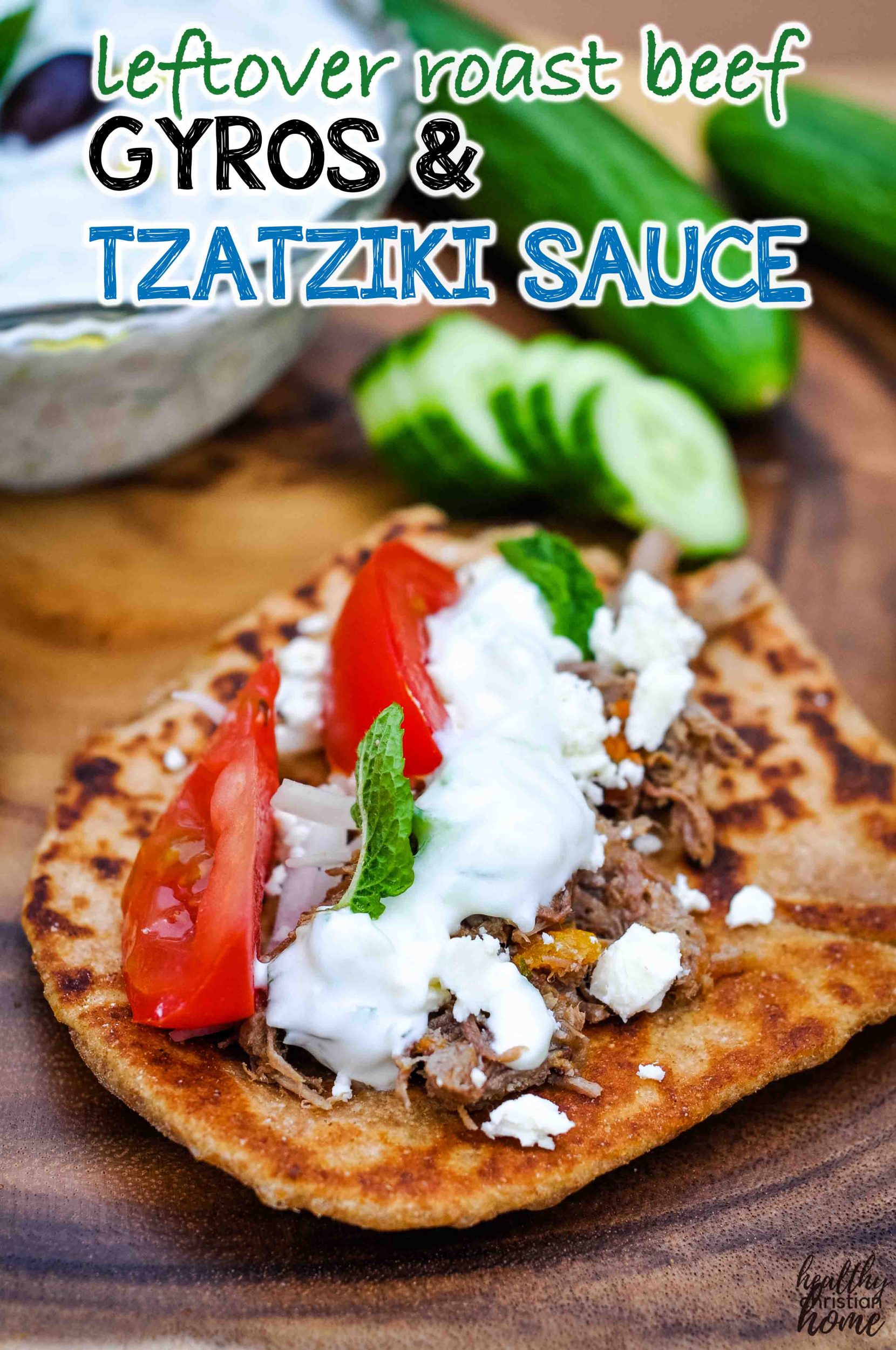 Roast beef gyros with topped with tzatziki sauce on a wooden board.