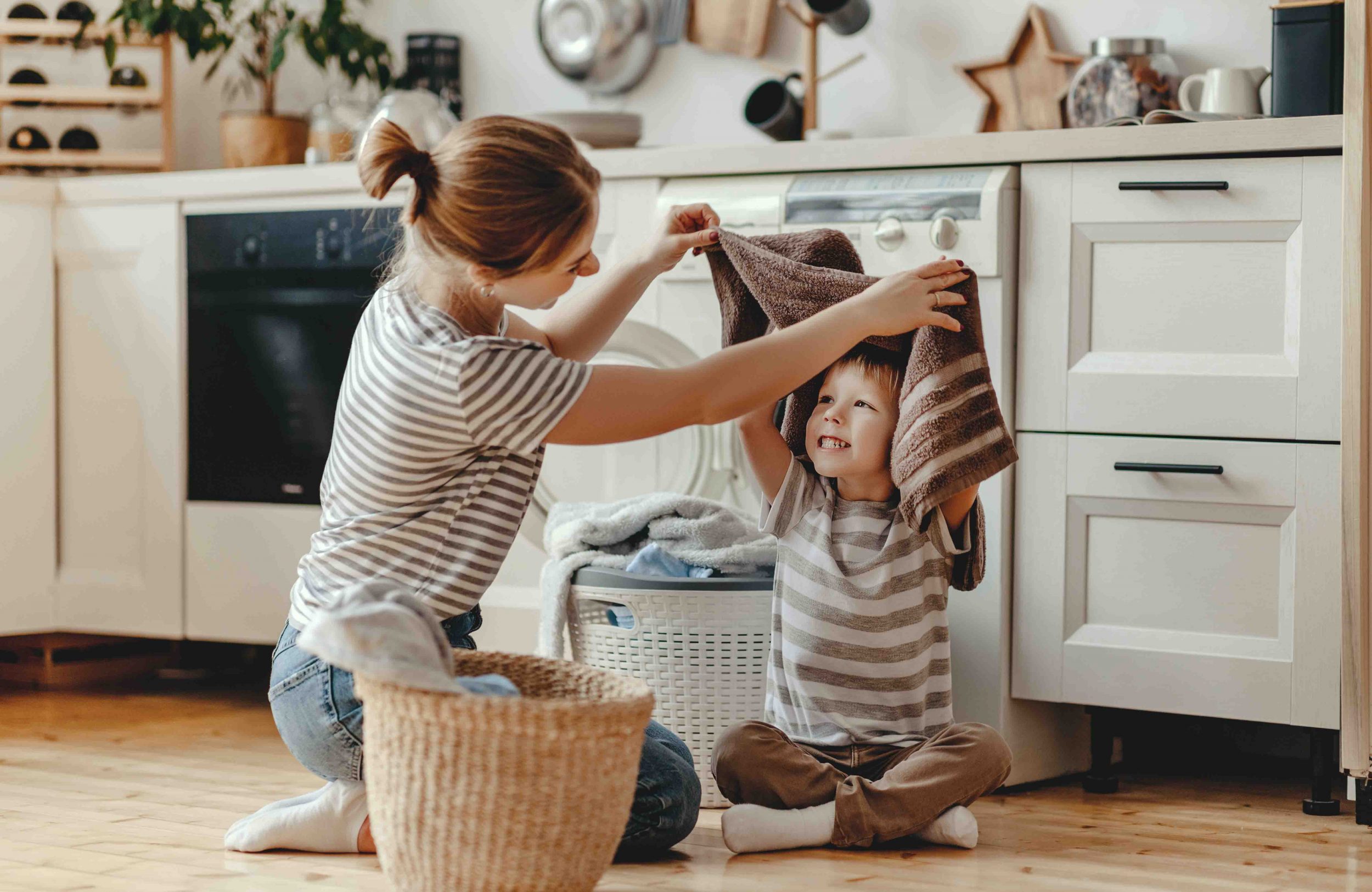 keeper at home doing laundry playing with her son