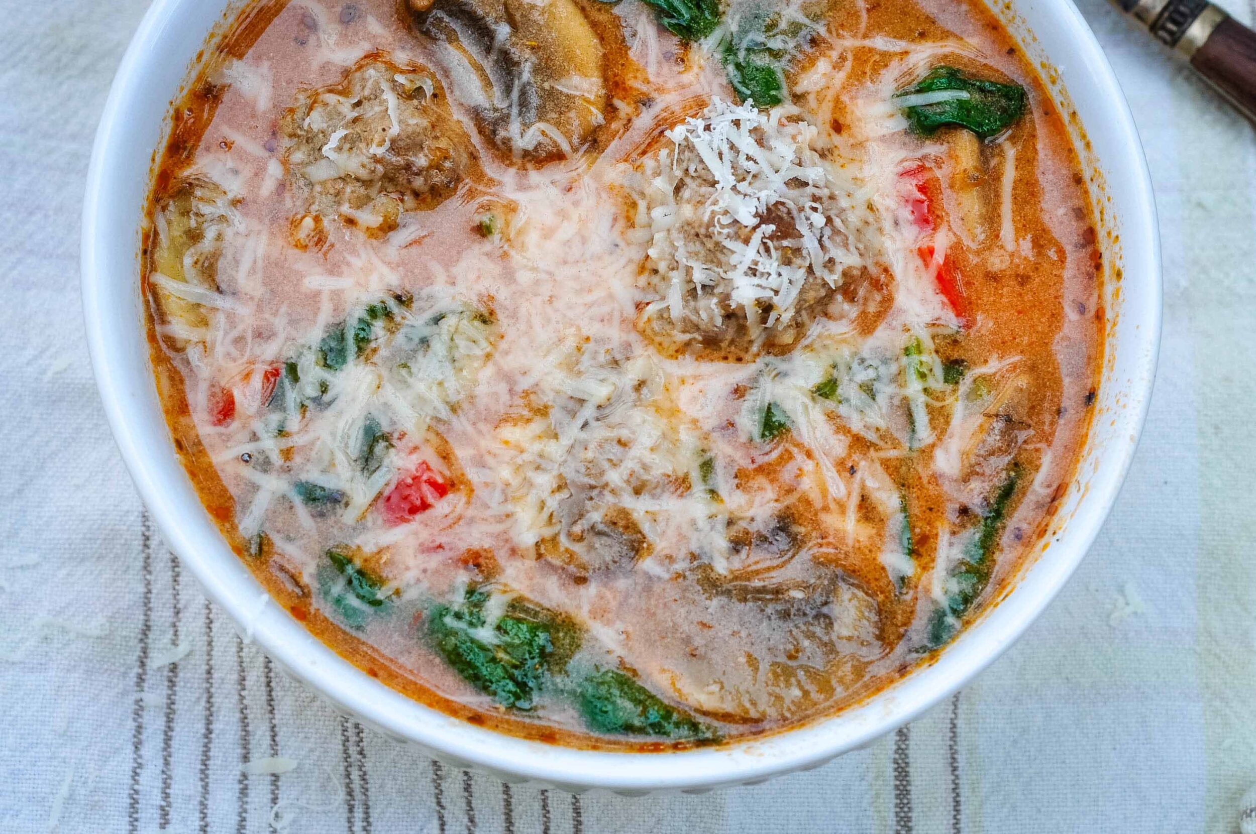 Cozy Italian meatball soup, a.k.a. pizza soup, in a white bowl.