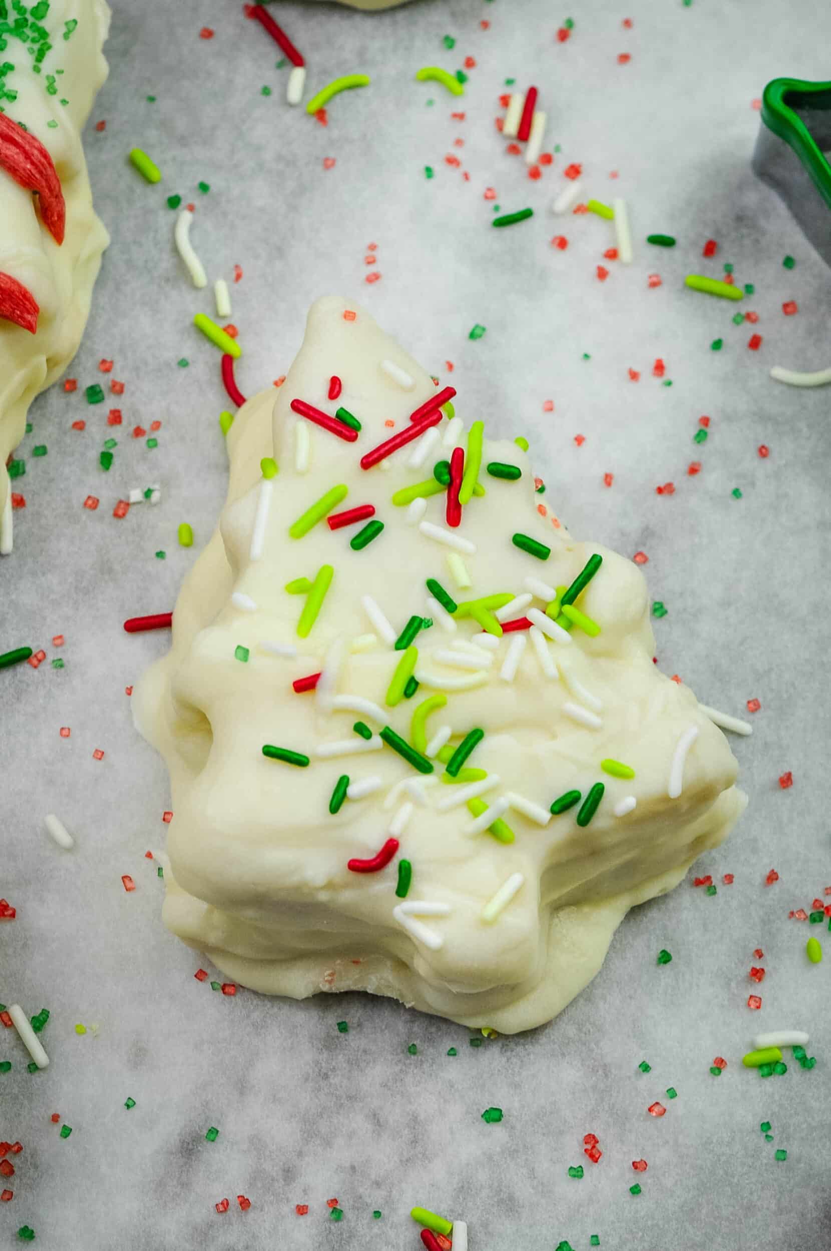 Christmas tree cake dipped in white chocolate, covered in sprinkles.