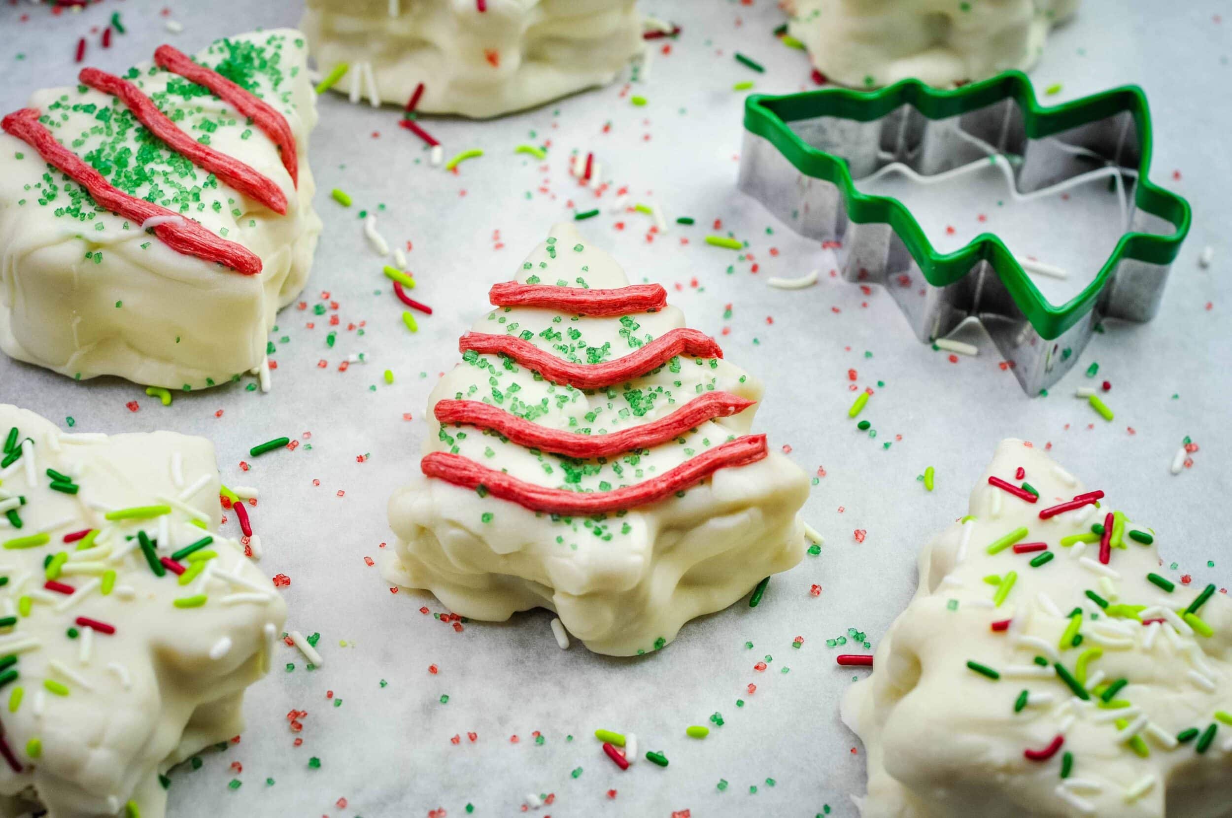 Christmas tree cake arranged on a board with other cakes surrounding it.