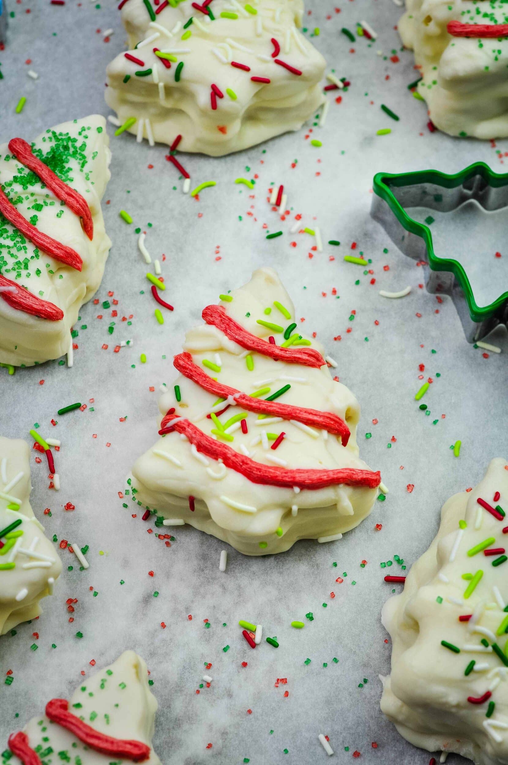 Various Christmas tree cakes arranged on a board with sprinkles.