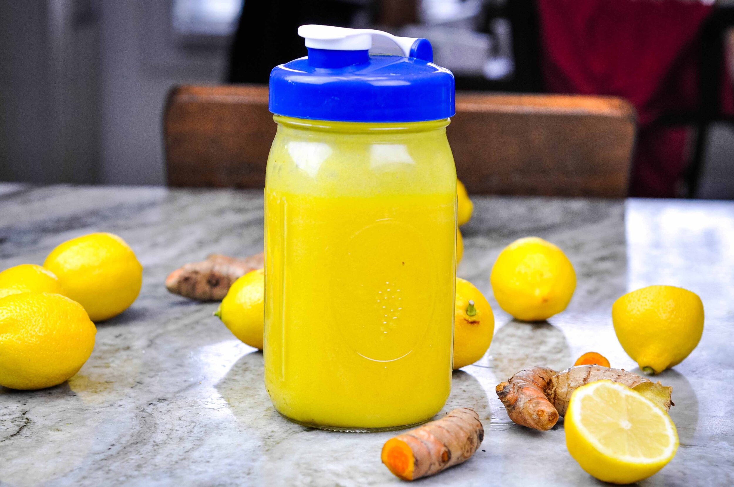 A jar of pineapple cough syrup surrounded by lemons, ginger, and turmeric.