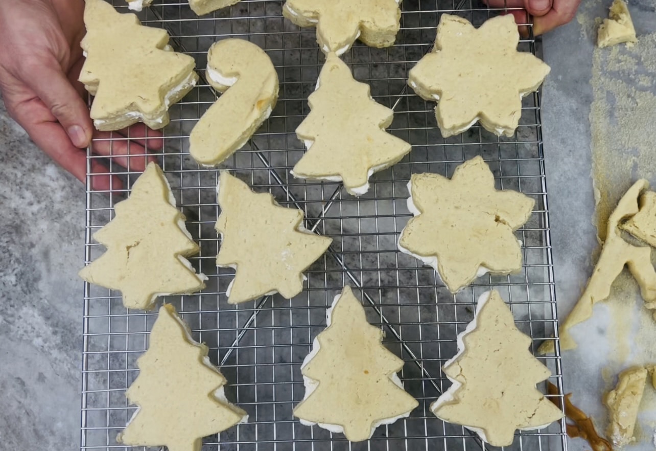 Process photo of Christmas cakes cut out with cookie cutters on a wire rack.
