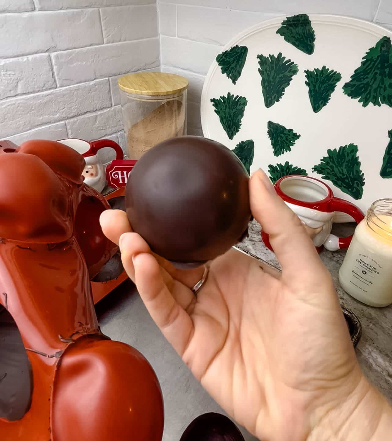 Person removing chocolate dome from its mold.