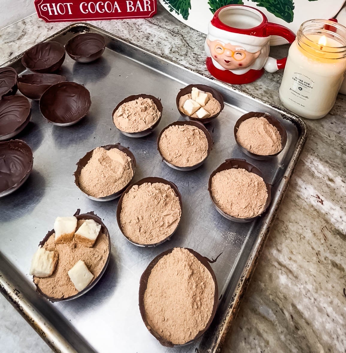Chocolate half domes being filled with cocoa mix and marshmallows.